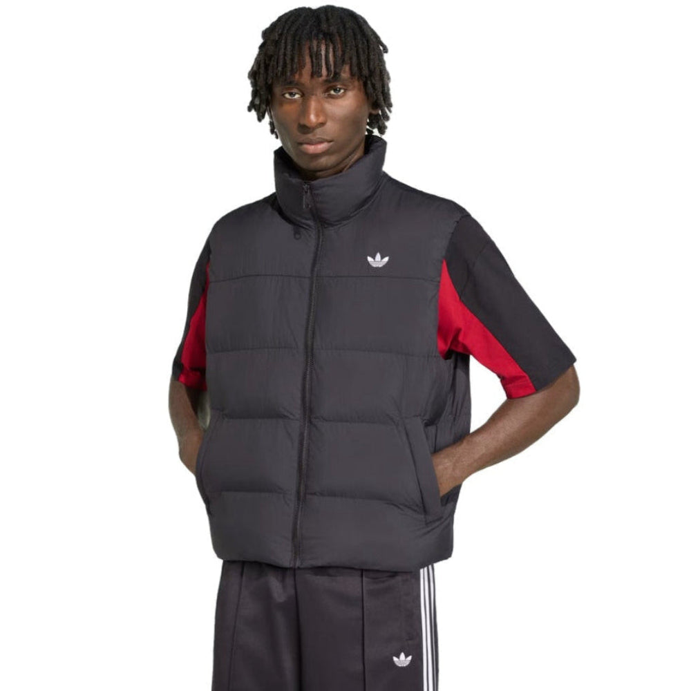 A model wearing a black Adidas puffer vest over a black short-sleeve track jacket with red color-blocked sleeves, paired with black Adidas track pants, on a solid white background.