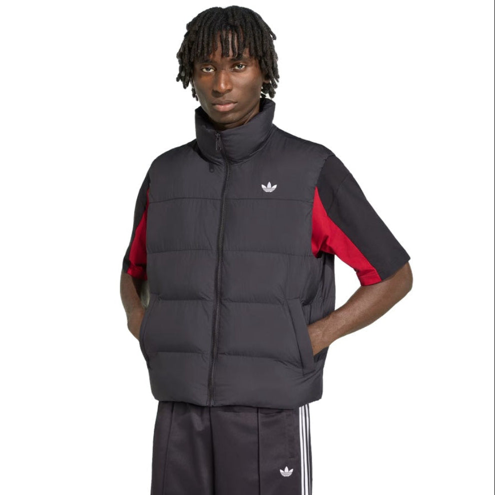 A model wearing a black Adidas puffer vest over a black short-sleeve track jacket with red color-blocked sleeves, paired with black Adidas track pants, on a solid white background.